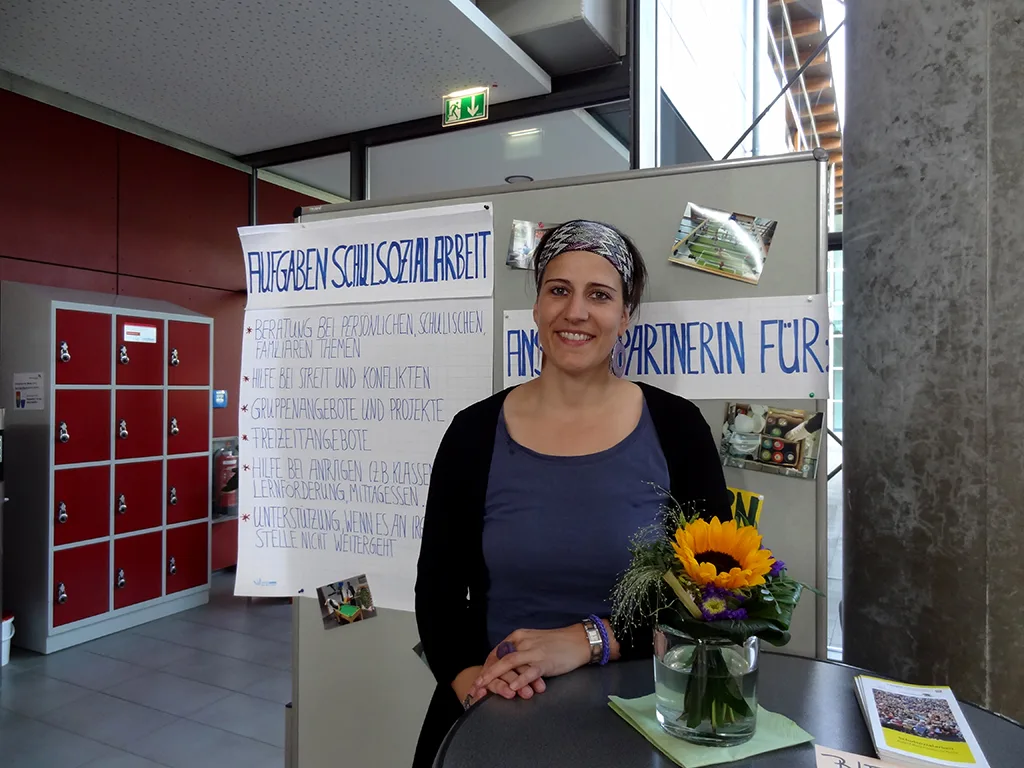 Person sitzt an einem Infotisch mit Sonnenblumen.